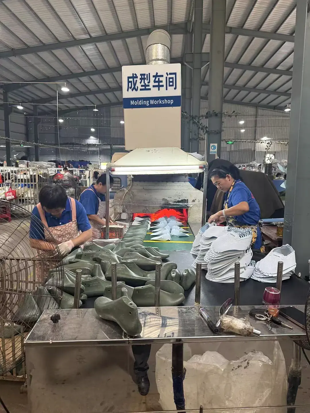 员工在鞋类成型工作台工作的竖幅视角